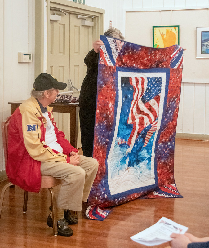 Lorraine Navone presents a quilt to Paul Miner.