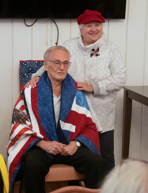 Carolyn Kuri presents a quilt to John Suhr.