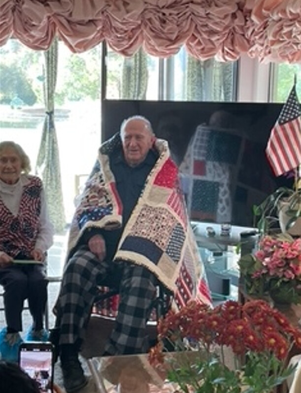 Marilee Kline presents a quilt to William Beardsley.