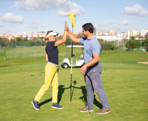 A man and woman golfer high-fiving.